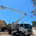 White truck with elevated boom in yard