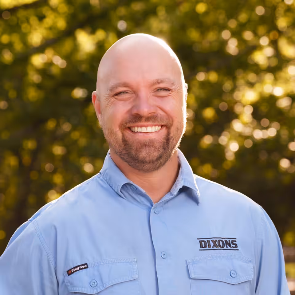 Smiling bald man in blue DIXONS shirt outdoors